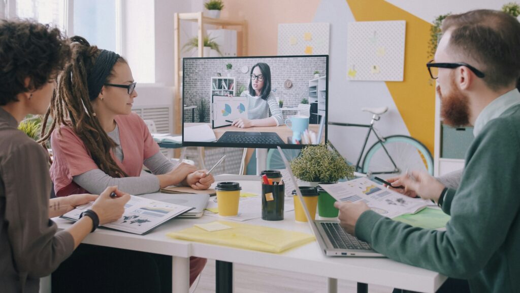 Colleagues in a meeting room talking with a remote colleague on a video call
